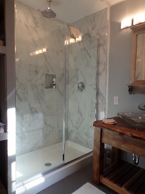 This is an example of a mid-sized transitional 3/4 bathroom in Nashville with open cabinets, medium wood cabinets, an alcove shower, gray tile, white tile, stone tile, grey walls, porcelain floors, a vessel sink and wood benchtops.