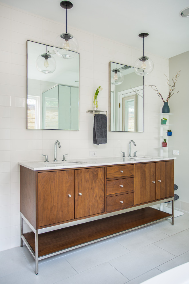 Design ideas for a mid-sized midcentury master bathroom in Dallas with brown cabinets, a freestanding tub, a corner shower, a two-piece toilet, white tile, ceramic tile, grey walls, porcelain floors, an undermount sink, marble benchtops, white floor, a hinged shower door, white benchtops and flat-panel cabinets.