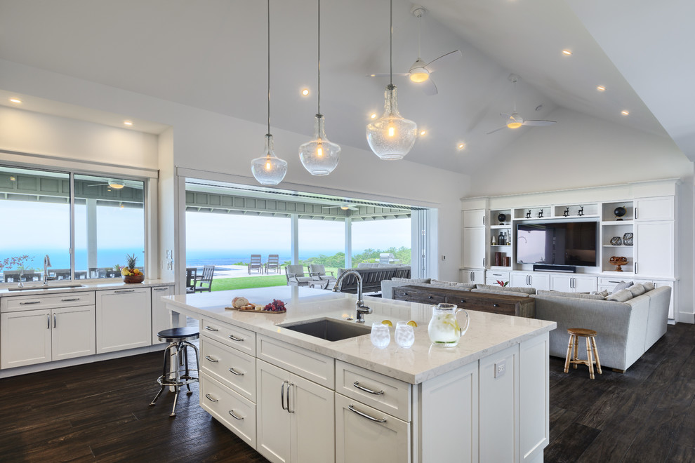 This is an example of a transitional kitchen in Hawaii with a single-bowl sink, shaker cabinets, white cabinets, granite benchtops, white splashback, subway tile splashback, stainless steel appliances, with island, dark hardwood floors and brown floor.