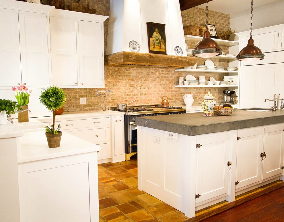 This is an example of a mid-sized country u-shaped eat-in kitchen in New York with a double-bowl sink, shaker cabinets, white cabinets, solid surface benchtops, multi-coloured splashback, brick splashback, stainless steel appliances, ceramic floors and with island.