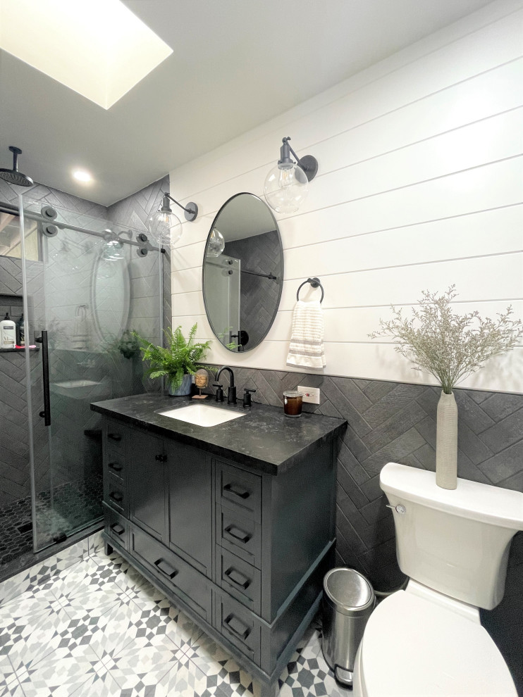 This is an example of a mid-sized modern master bathroom in San Diego with shaker cabinets, blue cabinets, an alcove shower, a two-piece toilet, black tile, porcelain tile, white walls, porcelain floors, an undermount sink, quartzite benchtops, multi-coloured floor, a sliding shower screen, black benchtops, a single vanity, a freestanding vanity and planked wall panelling.