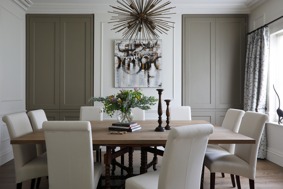 This is an example of a mid-sized transitional separate dining room in Kent with medium hardwood floors, no fireplace, brown floor, white walls and panelled walls.