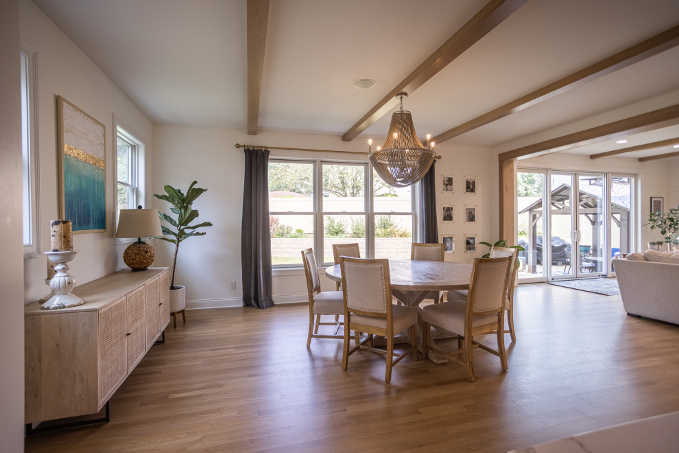 Esempio di una sala da pranzo aperta verso il soggiorno chic di medie dimensioni con pareti bianche, pavimento in legno massello medio, pavimento marrone e travi a vista