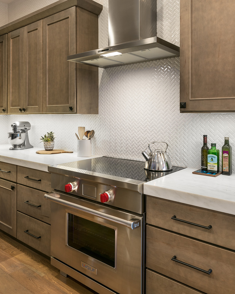 Inspiration for a mid-sized transitional l-shaped medium tone wood floor and brown floor open concept kitchen remodel in Phoenix with recessed-panel cabinets, marble countertops, white backsplash, an undermount sink, medium tone wood cabinets, ceramic backsplash, stainless steel appliances and an island