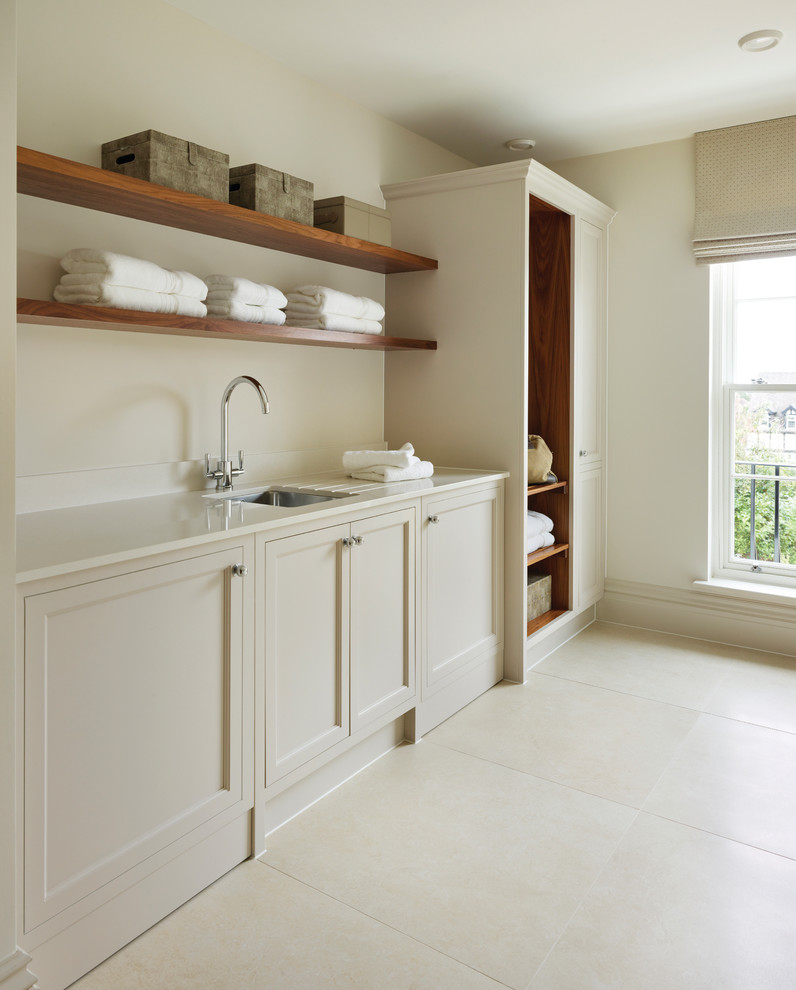 Photo of a transitional dedicated laundry room in Other with an undermount sink, recessed-panel cabinets, beige cabinets, beige walls, beige floor and white benchtop.