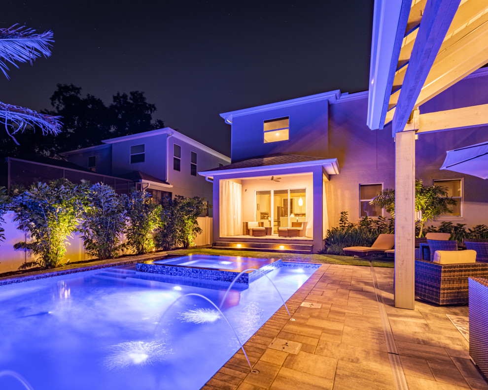 Photo of a mid-sized modern full sun backyard stone and vinyl fence landscaping in Tampa.