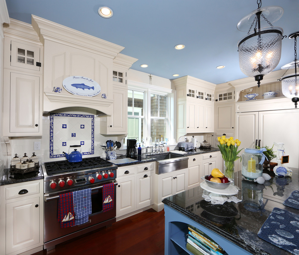This is an example of a traditional l-shaped kitchen in Philadelphia with a farmhouse sink, raised-panel cabinets, white cabinets, multi-coloured splashback and panelled appliances.