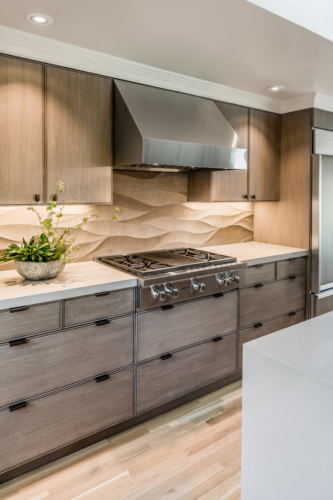 Large contemporary galley separate kitchen in San Francisco with an undermount sink, flat-panel cabinets, light wood cabinets, quartzite benchtops, beige splashback, porcelain splashback, panelled appliances, light hardwood floors, with island and beige floor.