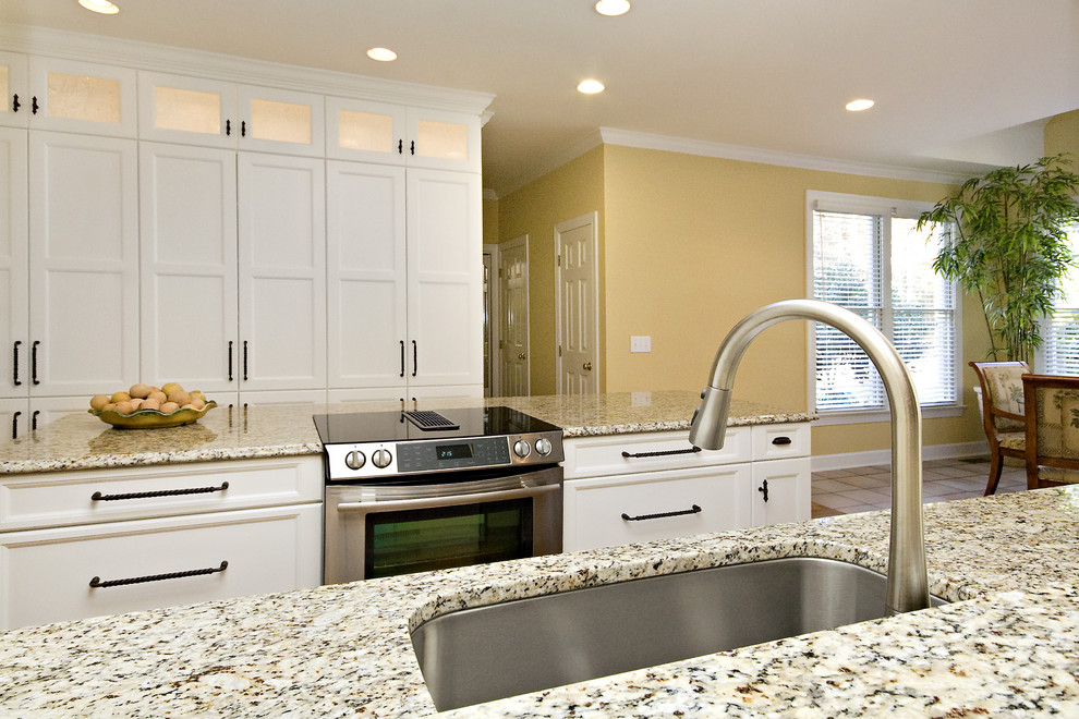 This is an example of a mid-sized transitional galley eat-in kitchen in Raleigh with an undermount sink, recessed-panel cabinets, white cabinets, granite benchtops, stainless steel appliances, multi-coloured splashback, glass tile splashback, medium hardwood floors, with island, orange floor and multi-coloured benchtop.