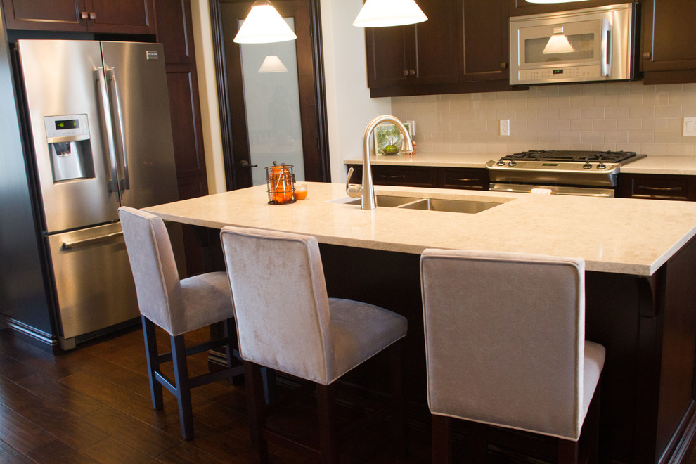 Inspiration for a transitional dark wood floor kitchen remodel with an undermount sink, shaker cabinets, dark wood cabinets, quartz countertops, gray backsplash, ceramic backsplash, stainless steel appliances and an island