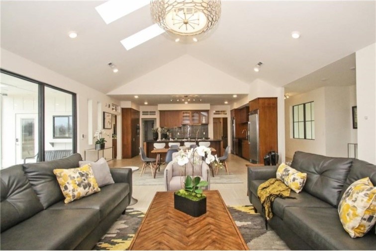 Photo of a modern open concept living room in Other with white walls, ceramic floors, a standard fireplace, a tile fireplace surround and white floor.