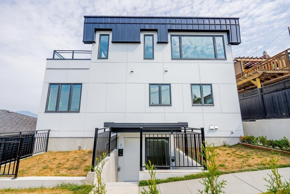 Example of a mid-sized white three-story mixed siding duplex exterior design in Vancouver with a mixed material roof and a black roof
