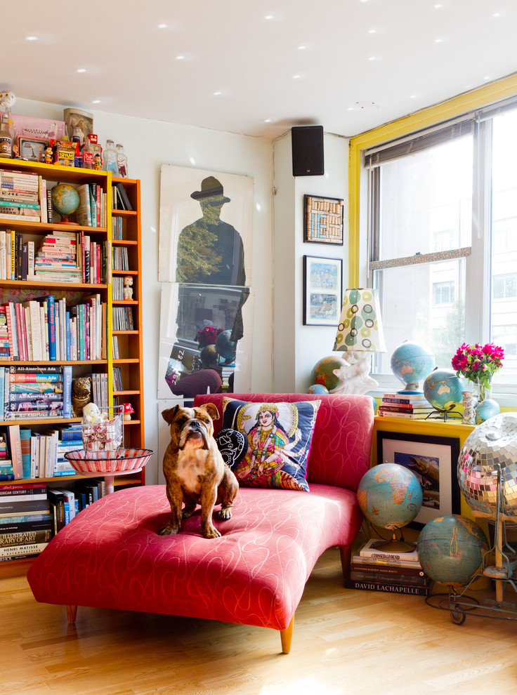Eclectic enclosed living room in New York with yellow walls and medium hardwood floors.