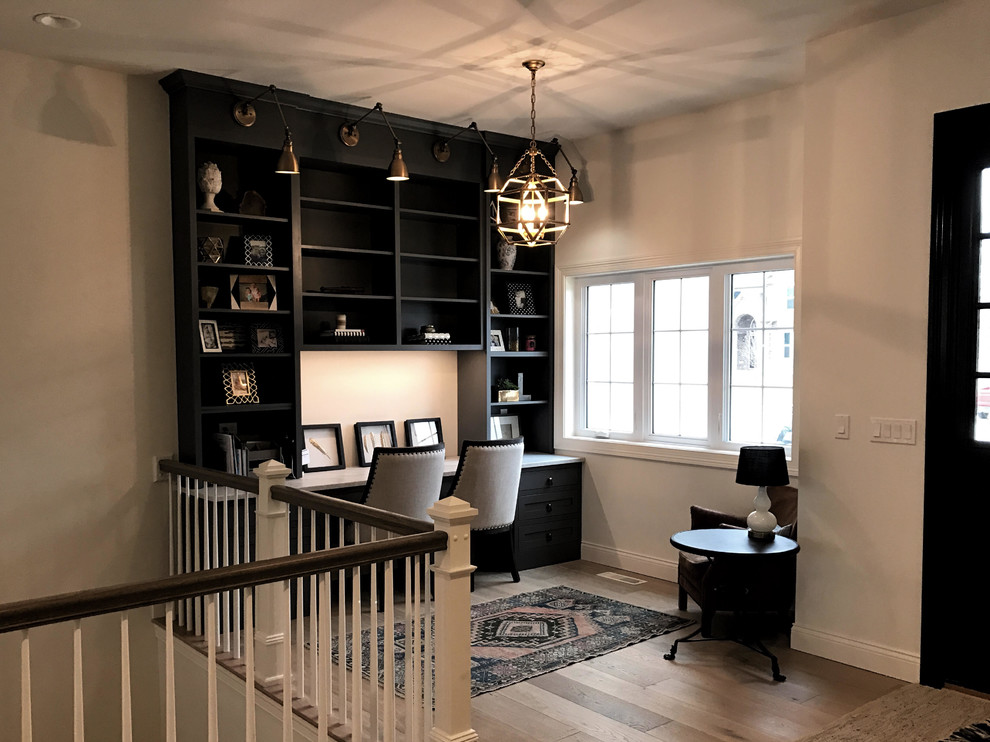 Inspiration for a small contemporary study room in Chicago with white walls, light hardwood floors and a built-in desk.