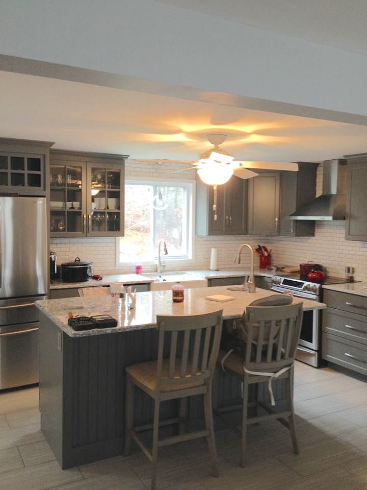 Inspiration for a mid-sized transitional l-shaped ceramic tile eat-in kitchen remodel in Boston with a farmhouse sink, recessed-panel cabinets, gray cabinets, granite countertops, white backsplash, subway tile backsplash, stainless steel appliances and an island