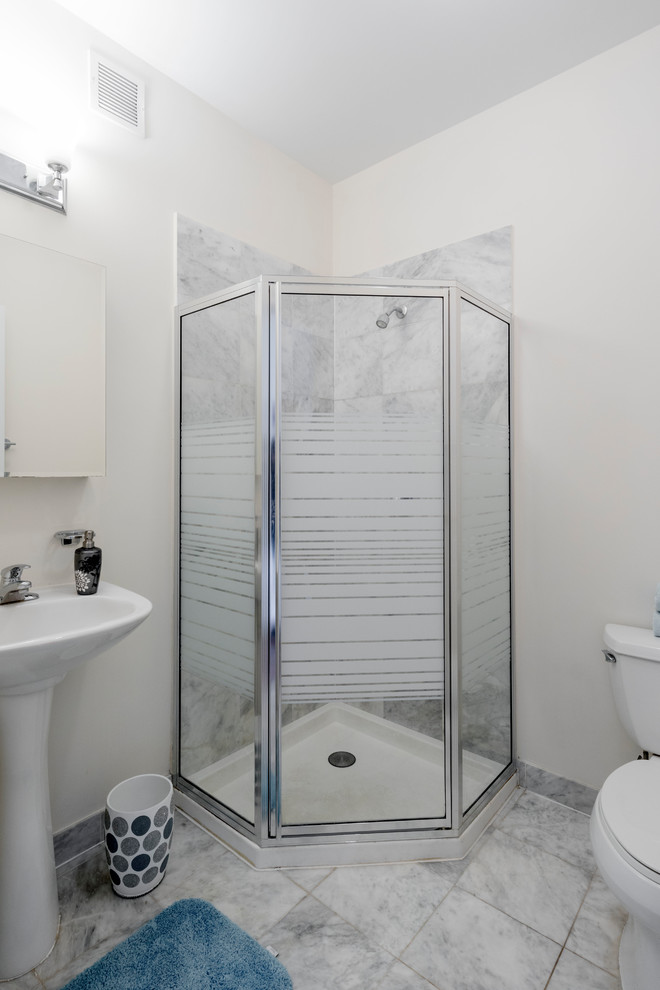 Photo of a small transitional 3/4 bathroom in New York with open cabinets, a corner shower, a two-piece toilet, white tile, marble, white walls, marble floors, a pedestal sink and white floor.