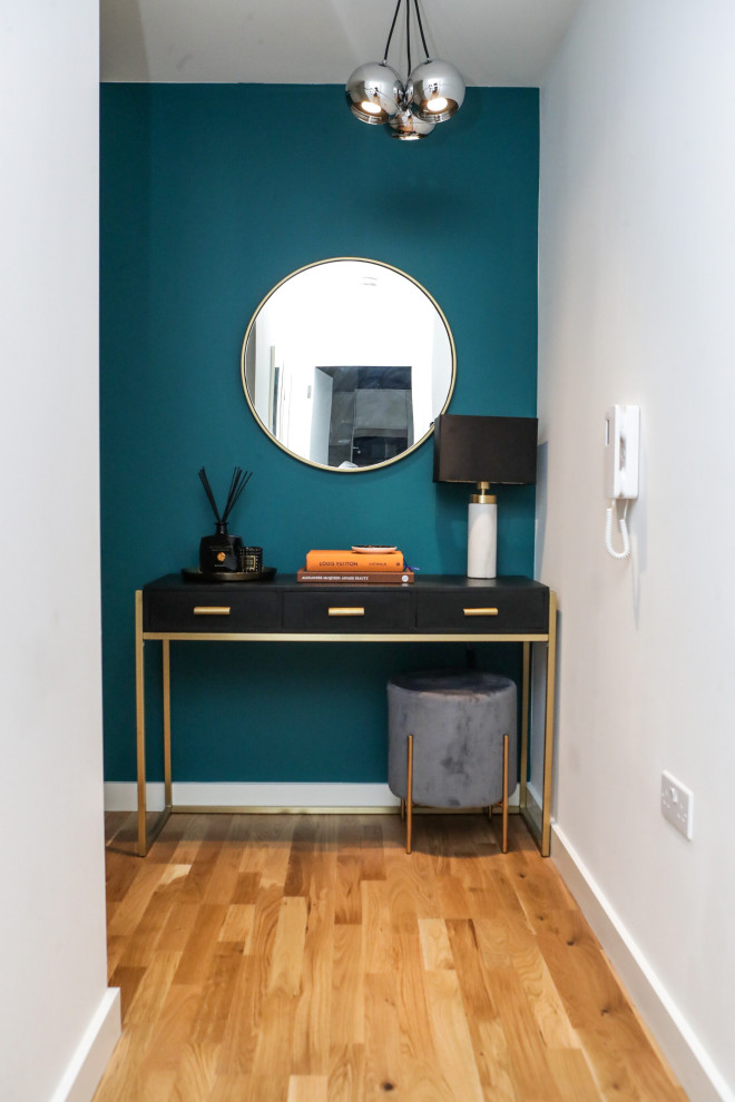 This is an example of a small modern hallway in London with green walls, light hardwood floors and brown floor.