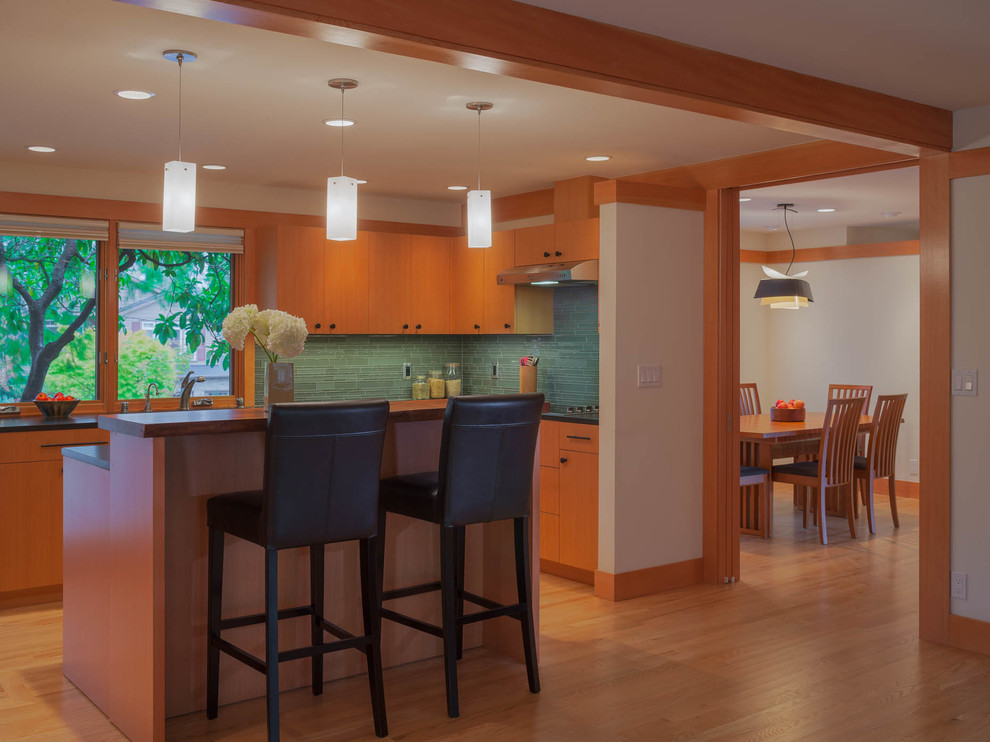 Open concept kitchen - mid-sized transitional l-shaped light wood floor open concept kitchen idea in Seattle with an undermount sink, flat-panel cabinets, medium tone wood cabinets, quartzite countertops, blue backsplash, glass tile backsplash, stainless steel appliances and an island
