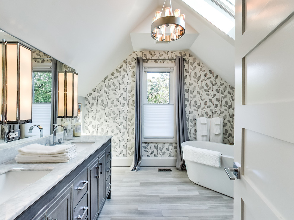 Inspiration for a large transitional master gray tile and limestone tile limestone floor and gray floor freestanding bathtub remodel in Toronto with furniture-like cabinets, gray cabinets, a two-piece toilet, white walls, an undermount sink, quartz countertops and a hinged shower door