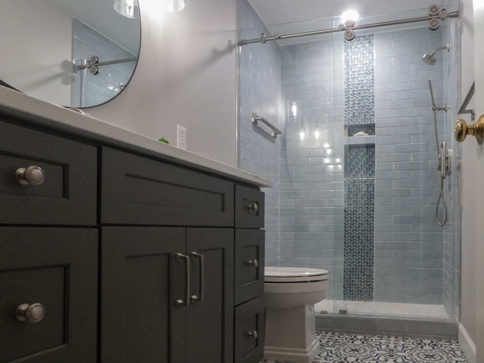 Mid-sized transitional kids bathroom in Atlanta with shaker cabinets, grey cabinets, an alcove shower, a two-piece toilet, blue tile, porcelain tile, grey walls, porcelain floors, an undermount sink, engineered quartz benchtops, multi-coloured floor, a sliding shower screen and white benchtops.