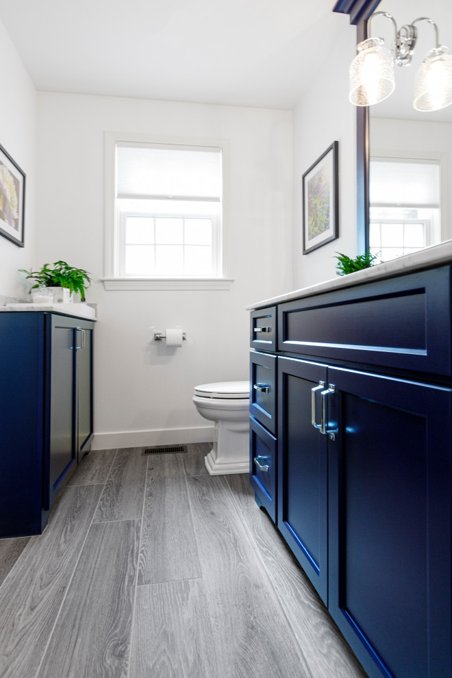 Пример оригинального дизайна: главная ванная комната в стиле неоклассика (современная классика) с фасадами в стиле шейкер, синими фасадами, душем в нише, раздельным унитазом, серой плиткой, мраморной плиткой, белыми стенами, полом из плитки под дерево, врезной раковиной, мраморной столешницей, серым полом, душем с распашными дверями, белой столешницей, тумбой под одну раковину и встроенной тумбой