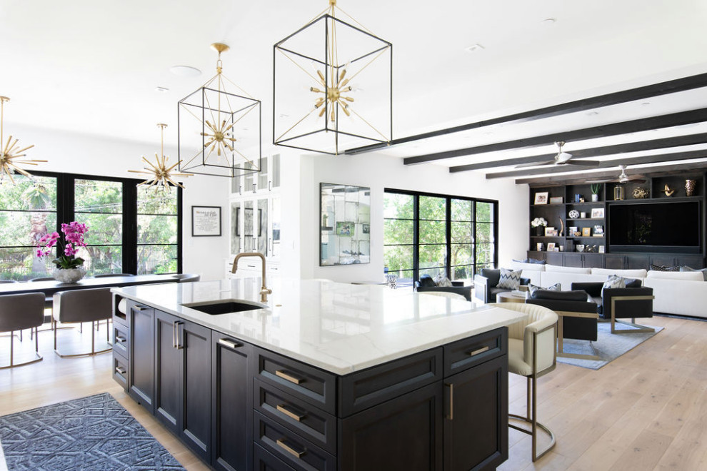 This is an example of a large transitional l-shaped open plan kitchen in Austin with shaker cabinets, white cabinets, quartzite benchtops, white splashback, marble splashback, stainless steel appliances, light hardwood floors, with island and white benchtop.