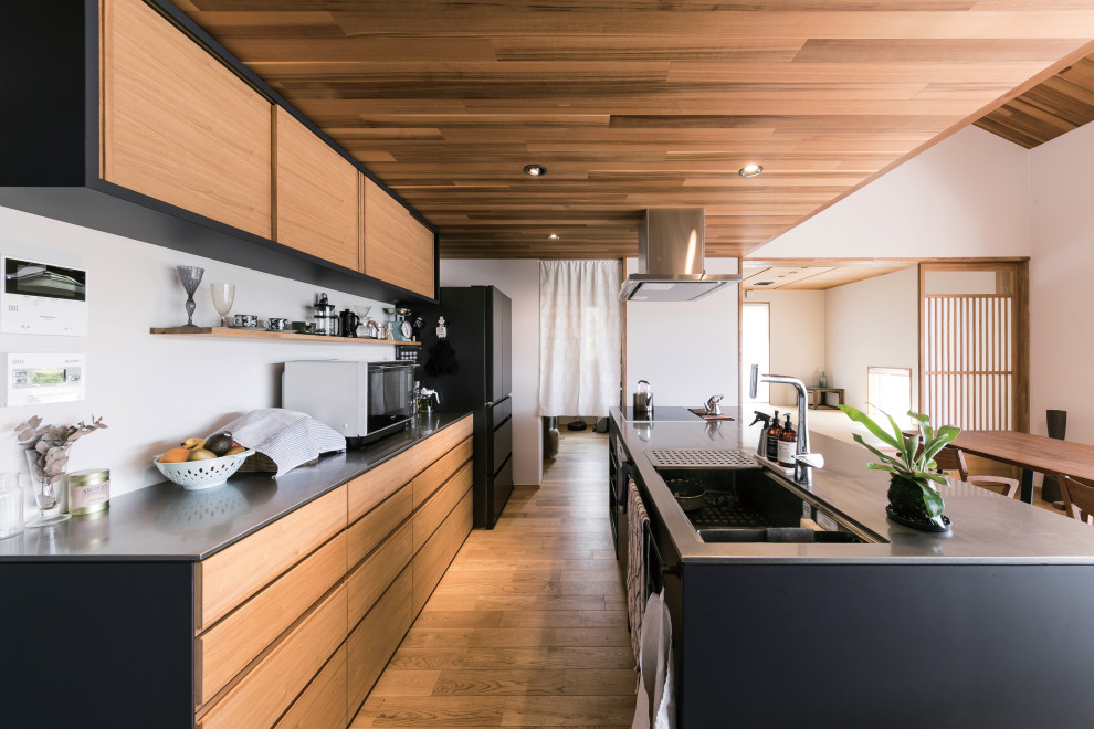 Aménagement d'une cuisine ouverte linéaire et encastrable scandinave en bois brun avec un évier intégré, un placard à porte plane, un plan de travail en inox, une crédence bleue, un sol en bois brun, îlot, un sol beige et un plafond en bois.