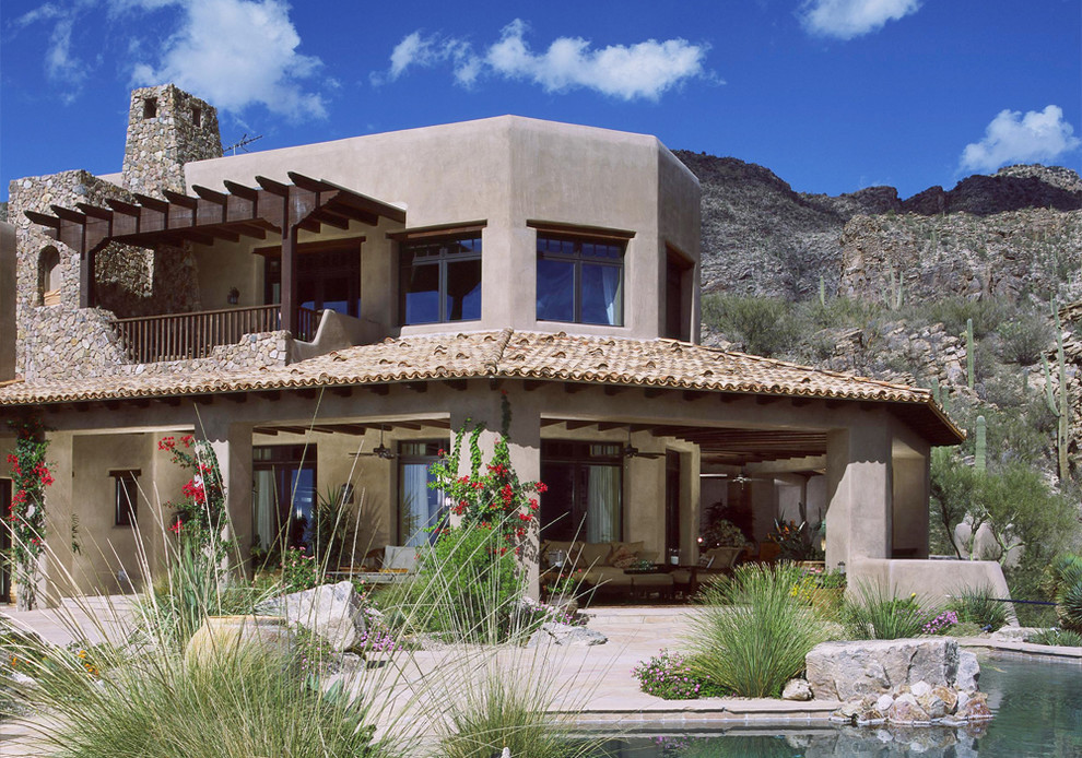 This is an example of a mediterranean two-storey adobe exterior in Phoenix with a flat roof.