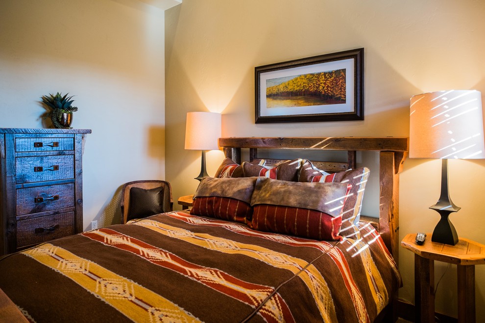 Mid-sized mountain style guest carpeted bedroom photo with beige walls, a corner fireplace and a stone fireplace