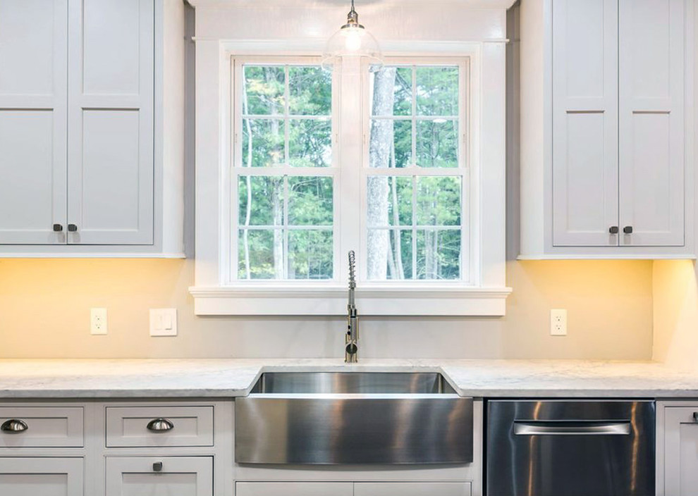 Example of a large transitional l-shaped dark wood floor and brown floor kitchen pantry design with a farmhouse sink, recessed-panel cabinets, white cabinets, quartz countertops, stainless steel appliances, an island and white countertops