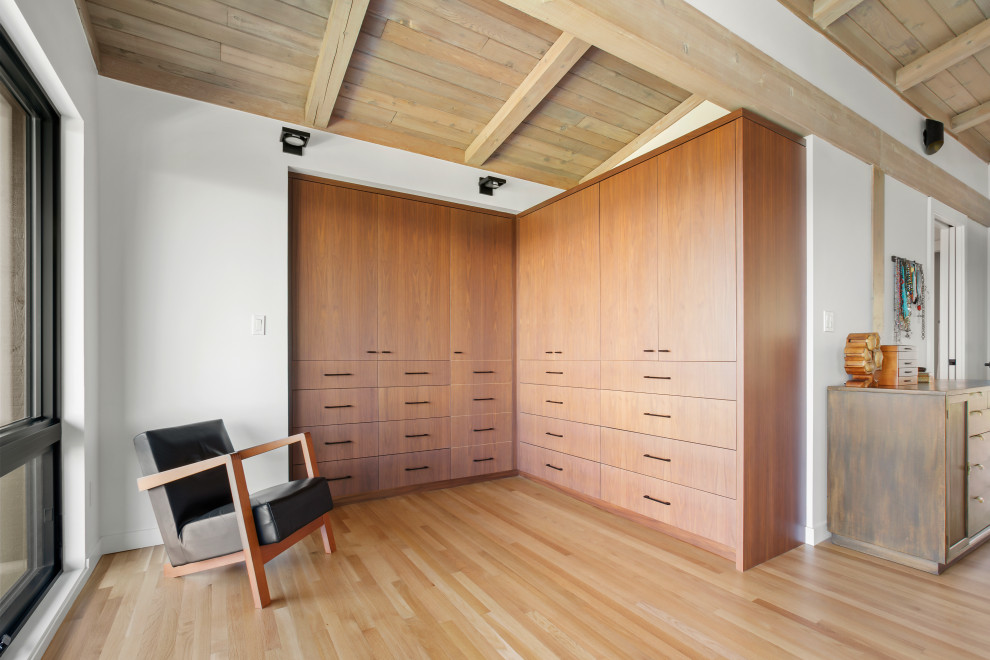 This is an example of a retro built-in wardrobe in Seattle with flat-panel cabinets, medium wood cabinets, light hardwood flooring and a wood ceiling.