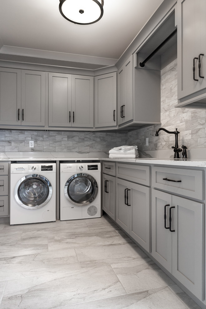 This is an example of a large transitional l-shaped dedicated laundry room in Atlanta with an undermount sink, recessed-panel cabinets, grey cabinets, marble benchtops, grey walls, ceramic floors, a side-by-side washer and dryer, grey floor and grey benchtop.