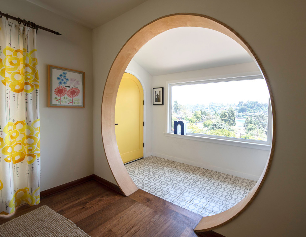 ロサンゼルスにある高級な広いエクレクティックスタイルのおしゃれな玄関ロビー (白い壁、コンクリートの床、黄色いドア、ベージュの床、三角天井) の写真