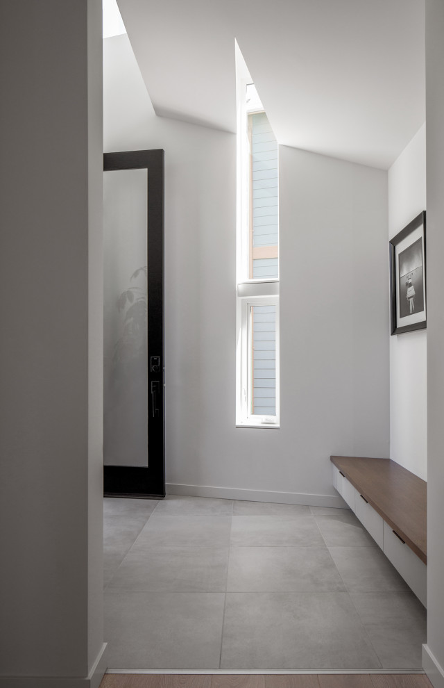 Diseño de distribuidor abovedado de tamaño medio con paredes blancas, suelo de baldosas de porcelana, puerta simple, puerta negra y suelo gris