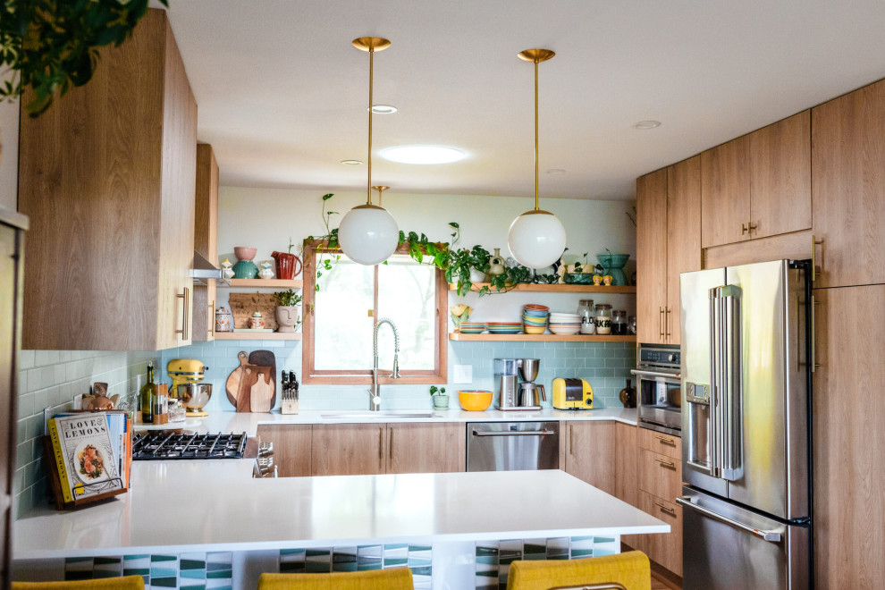 Foto på ett mellanstort retro vit kök, med släta luckor, skåp i ljust trä, bänkskiva i kvarts, blått stänkskydd, stänkskydd i keramik, rostfria vitvaror och en halv köksö
