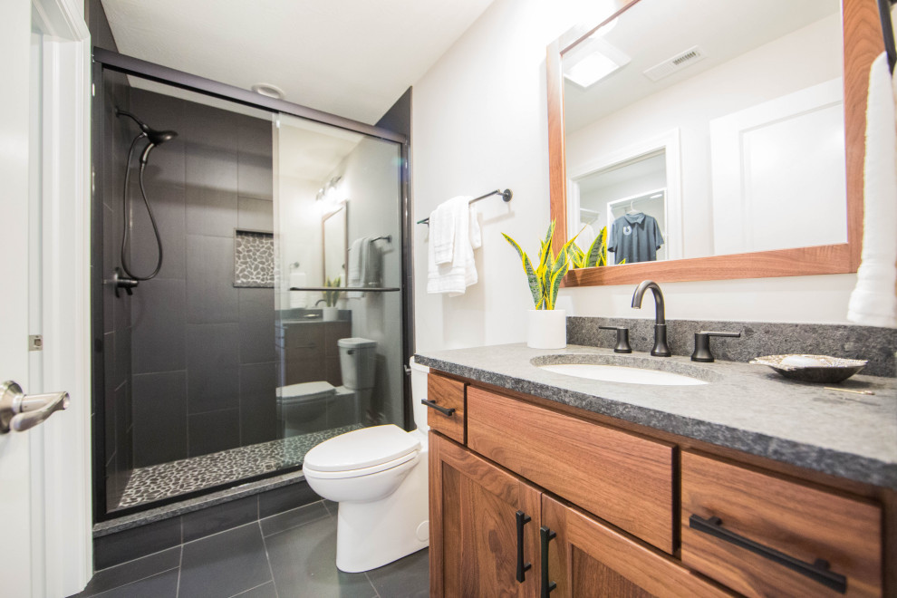 Large classic bathroom in Indianapolis with recessed-panel cabinets, brown cabinets, an alcove shower, a two-piece toilet, black tiles, porcelain tiles, white walls, porcelain flooring, a submerged sink, granite worktops, black floors, a sliding door, grey worktops, a single sink and a freestanding vanity unit.