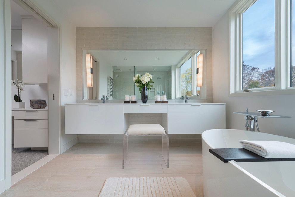Design ideas for a large contemporary master bathroom in Boston with beaded inset cabinets, white cabinets, a freestanding tub, white tile, mosaic tile, engineered quartz benchtops, a corner shower, a wall-mount toilet, white walls, porcelain floors and a wall-mount sink.