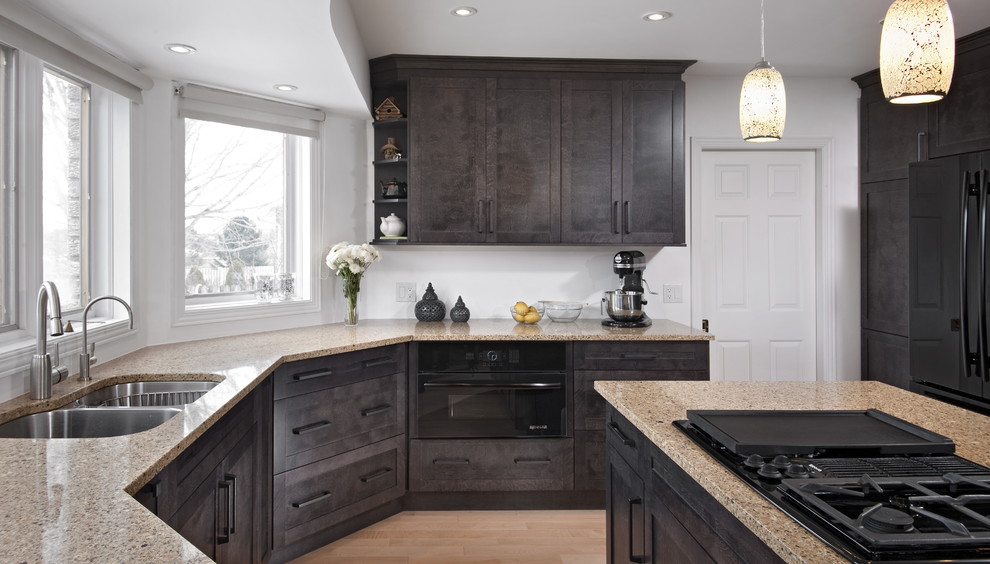 Mid-sized transitional u-shaped light wood floor eat-in kitchen photo with shaker cabinets, dark wood cabinets, quartz countertops, black appliances, a peninsula and beige countertops