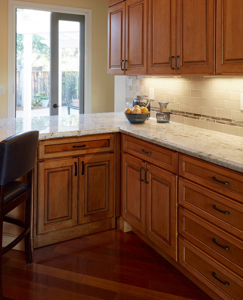 This is an example of a large arts and crafts u-shaped eat-in kitchen in San Francisco with an undermount sink, raised-panel cabinets, medium wood cabinets, granite benchtops, beige splashback, subway tile splashback, stainless steel appliances, medium hardwood floors and a peninsula.