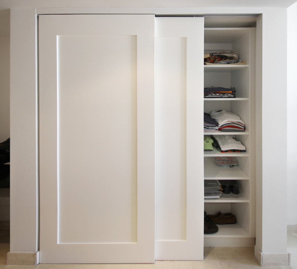 Small contemporary gender-neutral built-in wardrobe in Miami with flat-panel cabinets, white cabinets, porcelain floors and beige floor.