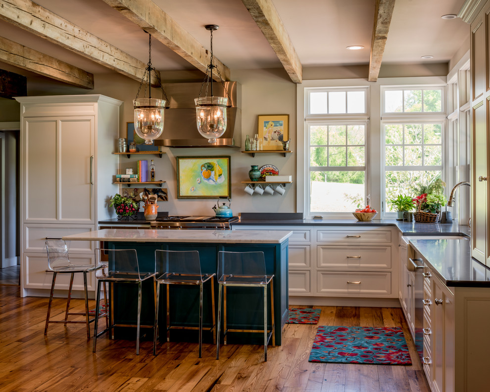 Design ideas for a mid-sized traditional l-shaped open plan kitchen in Philadelphia with a farmhouse sink, recessed-panel cabinets, white cabinets, window splashback, stainless steel appliances, medium hardwood floors, with island and brown floor.