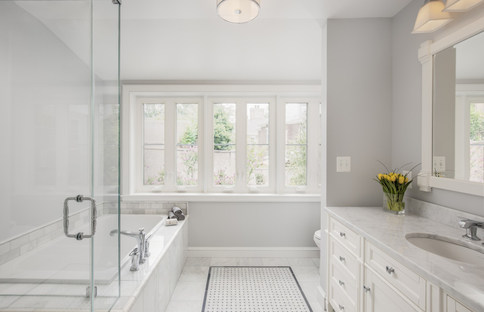 Photo of a large traditional master bathroom in DC Metro with recessed-panel cabinets, white cabinets, a drop-in tub, a corner shower, gray tile, marble, grey walls, marble floors, an undermount sink, marble benchtops, grey floor, a hinged shower door, white benchtops, a single vanity and a freestanding vanity.