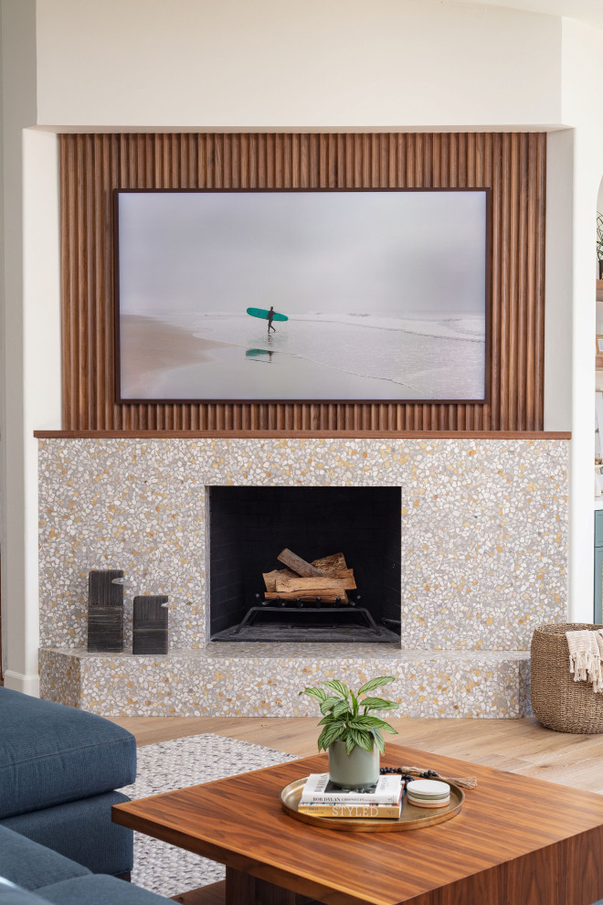 サンディエゴにある広いビーチスタイルのおしゃれなリビング (白い壁、淡色無垢フローリング、標準型暖炉、コンクリートの暖炉まわり、壁掛け型テレビ、パネル壁) の写真