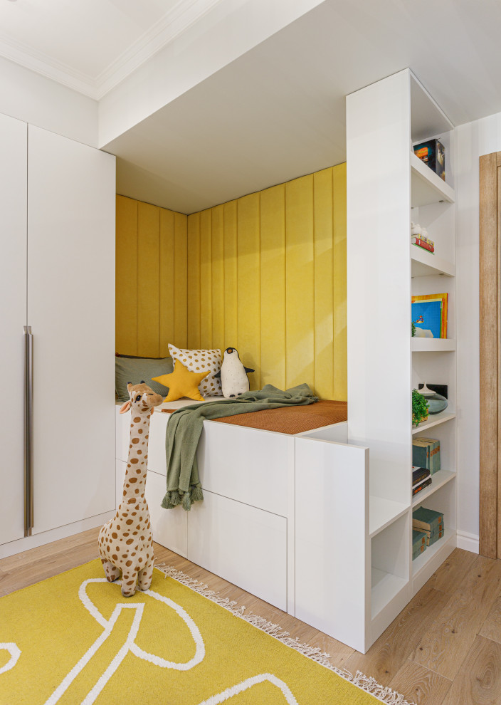 Idée de décoration pour une chambre d'enfant de 4 à 10 ans design de taille moyenne avec un mur blanc, un sol en bois brun et un sol beige.