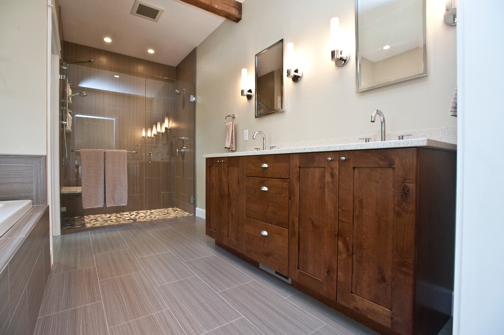 Example of a mid-sized transitional master gray tile and ceramic tile porcelain tile and brown floor drop-in bathtub design with an undermount sink, shaker cabinets, quartz countertops, gray walls, dark wood cabinets and a hinged shower door