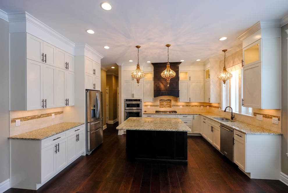 Inspiration for a large transitional u-shaped dark wood floor and brown floor eat-in kitchen remodel with an undermount sink, recessed-panel cabinets, white cabinets, granite countertops, beige backsplash, stainless steel appliances and an island