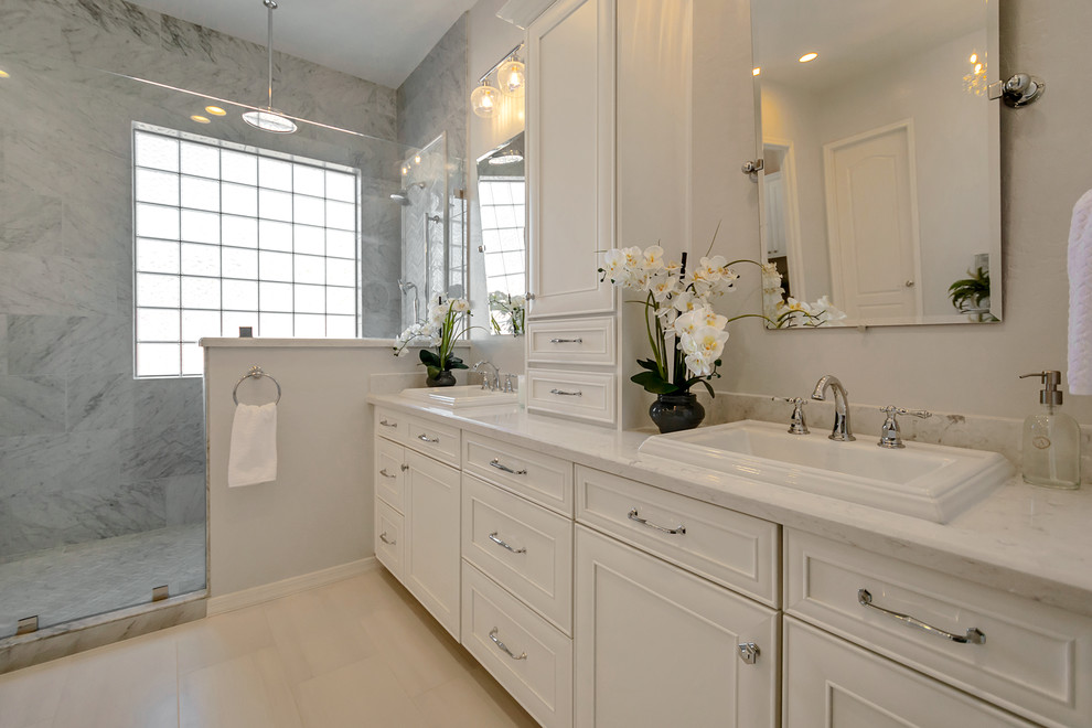 Freestanding bathtub - large transitional master gray tile and marble tile porcelain tile and gray floor freestanding bathtub idea in Phoenix with recessed-panel cabinets, white cabinets, gray walls, a drop-in sink, quartz countertops and white countertops