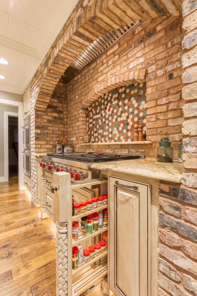 Enclosed kitchen - large transitional u-shaped medium tone wood floor enclosed kitchen idea in Austin with a double-bowl sink, raised-panel cabinets, white cabinets, granite countertops, beige backsplash, stone tile backsplash, paneled appliances and an island