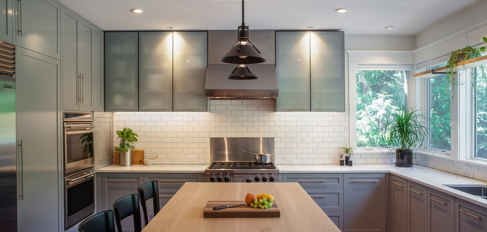 Inspiration for a transitional eat-in kitchen in Portland with an undermount sink, shaker cabinets, grey cabinets, quartz benchtops, white splashback, subway tile splashback, stainless steel appliances, medium hardwood floors, with island and white benchtop.