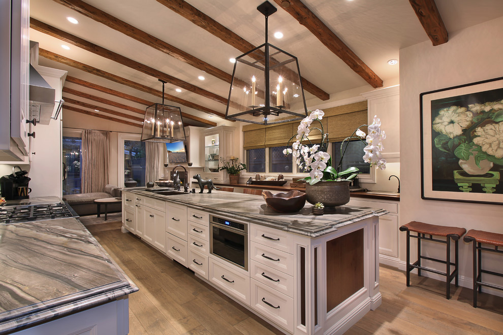 Inspiration for a mediterranean kitchen in Orange County with recessed-panel cabinets, white cabinets and with island.